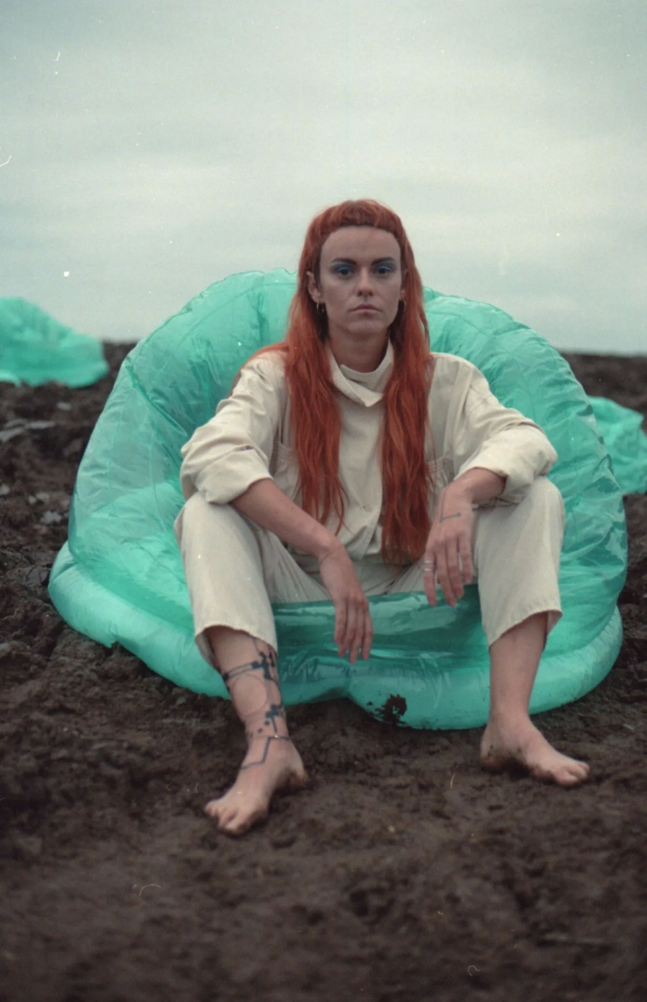 Aleksandra in a mint inflatable armchair on raw ploughed field